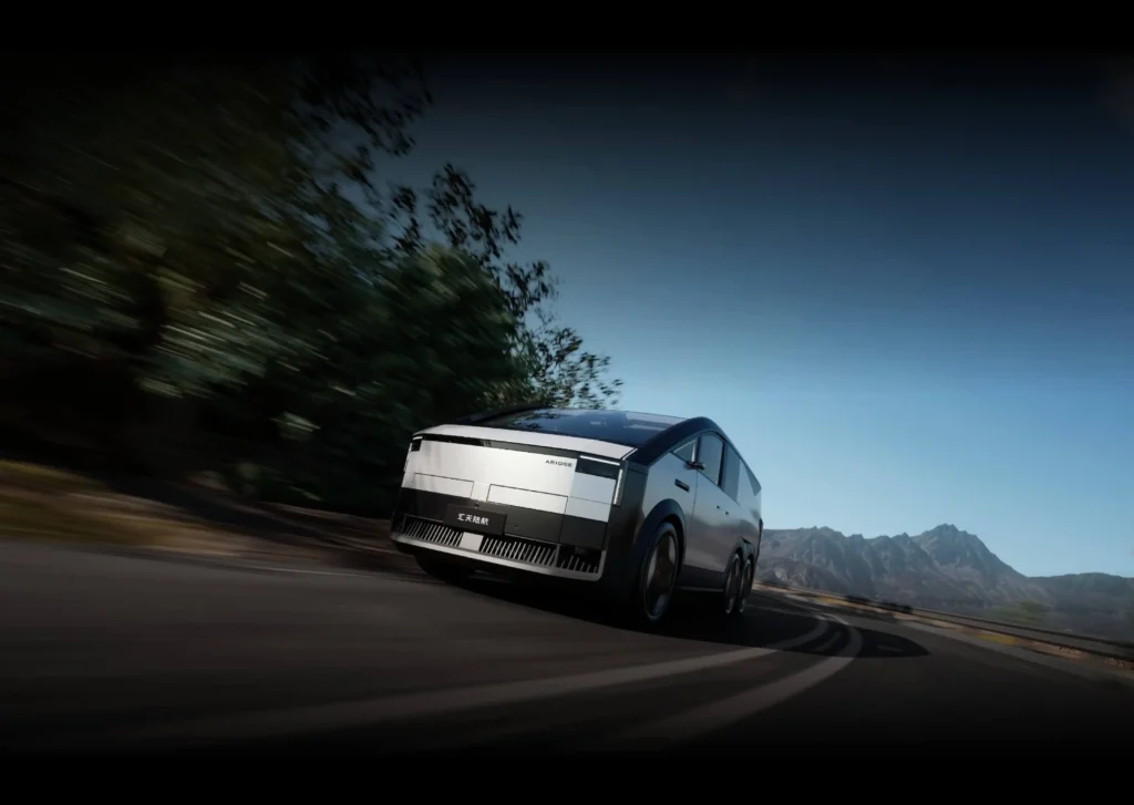 샤오펑 에어로트 육지 항공모함 지상 모듈(6륜 트럭)이 도로를 역동적으로 주행하는 전면 모습. 사이버트럭 스타일의 각진 미래지향적 디자인과 전면을 가로지르는 일자형 LED 헤드라이트가 강조된 사진.