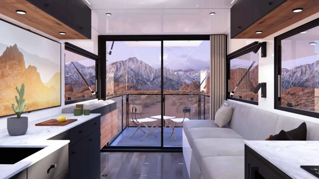 사이버트레일러 거실과 주방에서 유리 슬라이딩 도어 너머로 산맥과 야외 데크가 보이는 실내 인테리어 렌더링