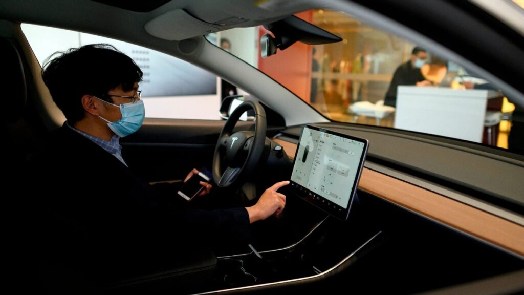 마스크를 착용한 운전자가 중앙 스크린을 조작하는 모습, FSD 운전자 인터페이스