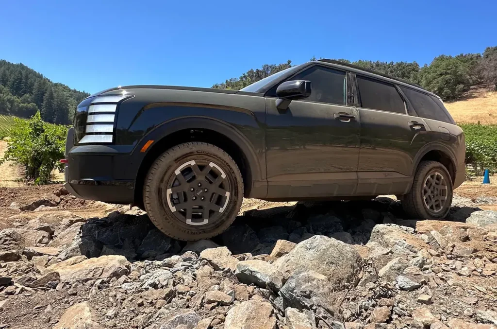 2026 Hyundai Palisade XRT PRO climbing over large rocks in an off-road environment.
