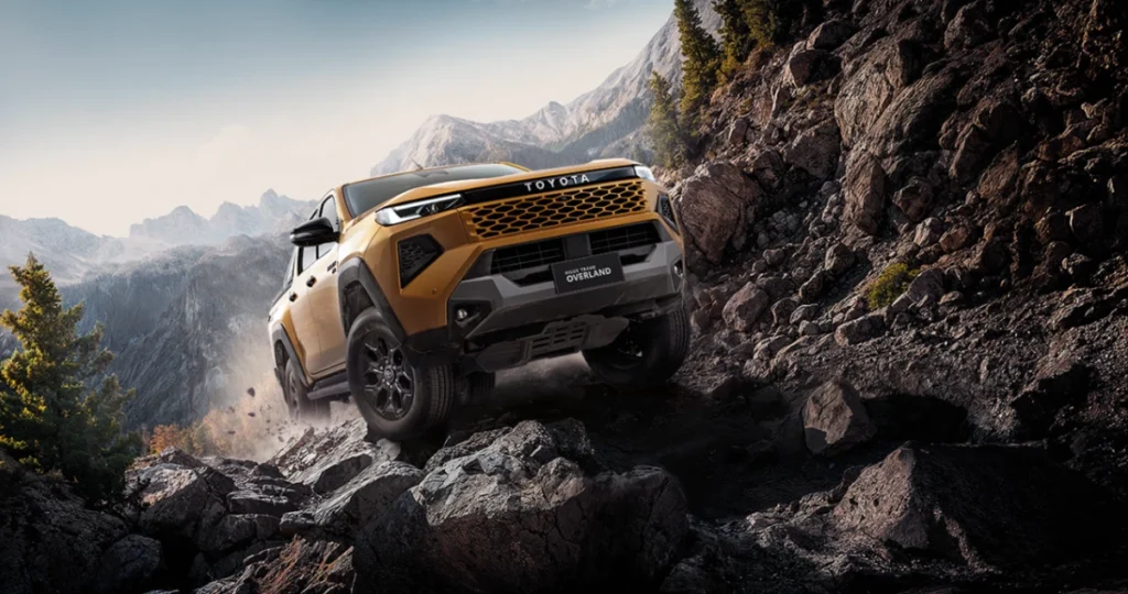 Hilux Travo-e Range Gold Toyota Hilux Travo climbing steep rocks on an off-road trail.